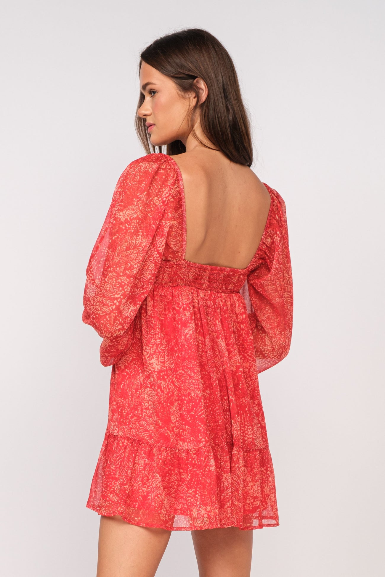 woman wearing a red floral print mini dress with puff sleeves and an open back