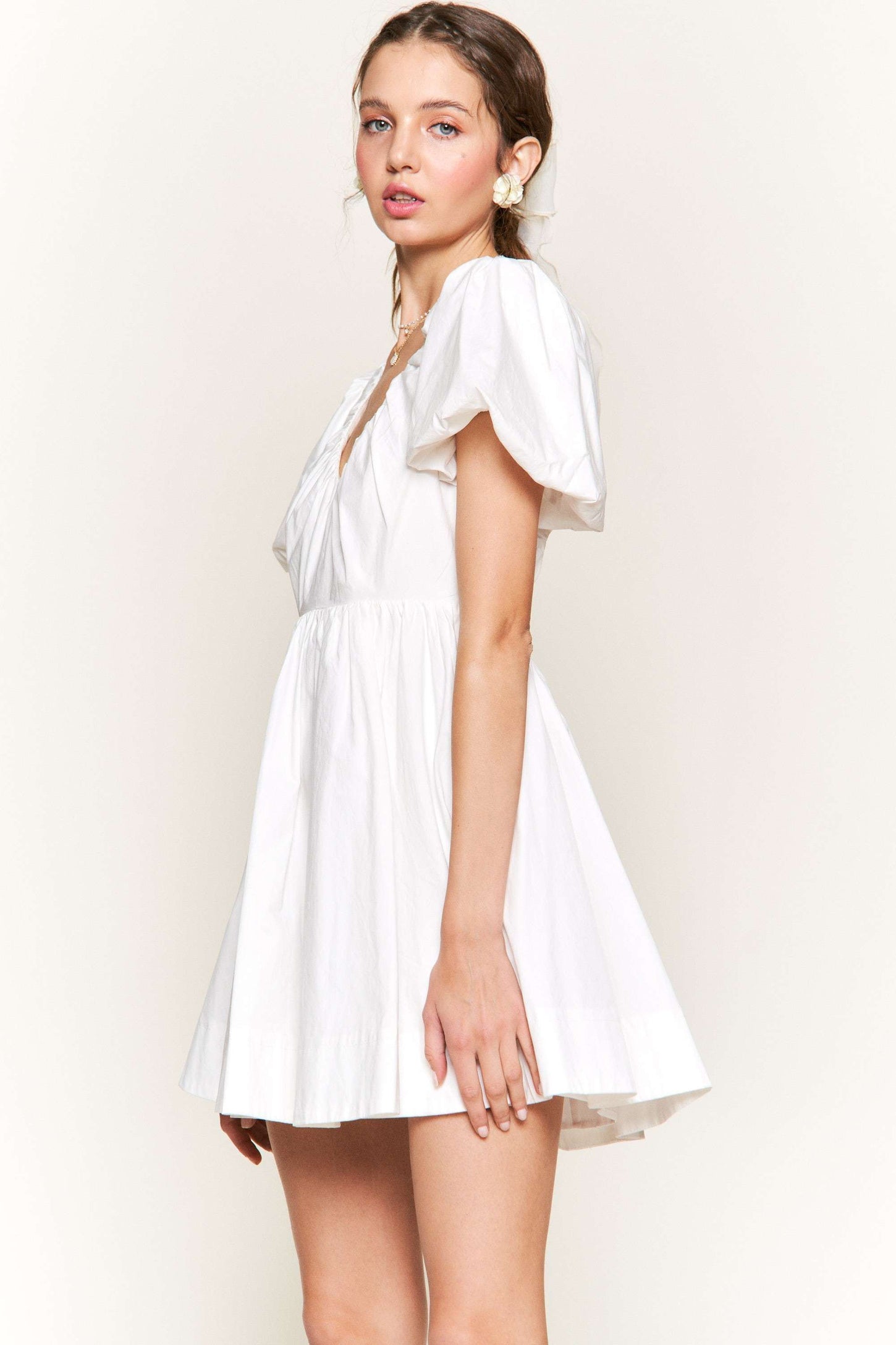 woman wearing a white short puff sleeve dress with a v-neck and flared skirt
