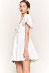 woman wearing a white short puff sleeve dress with a v-neck and flared skirt