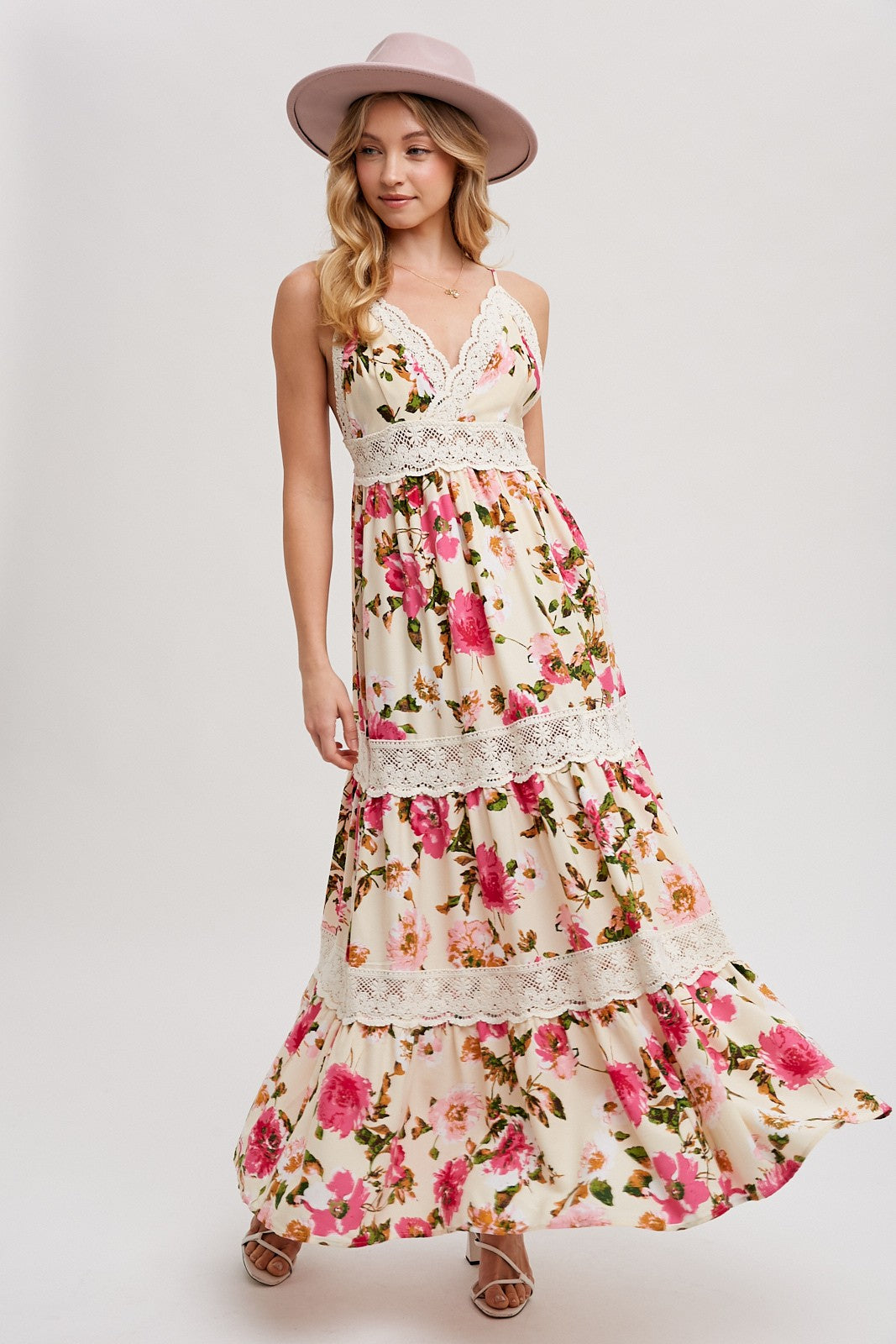 woman wearing a floral maxi dress with lace detailing and a wide-brimmed pink hat