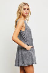 woman wearing a gray denim sleeveless dress with side pockets and a flared silhouette