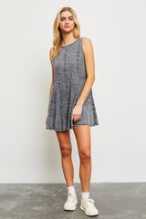 woman wearing a gray sleeveless denim dress with a flared hem and frayed edges