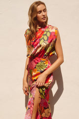 woman wearing a colorful floral print maxi dress with a side slit and a draped neckline